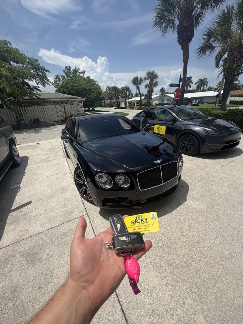 Bentley keys held in front of a black Bentley and the Ricky Locksmith service vehicle