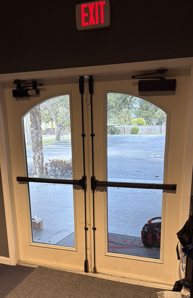 Double fire exit doors with vertical-rod panic bars and door closers