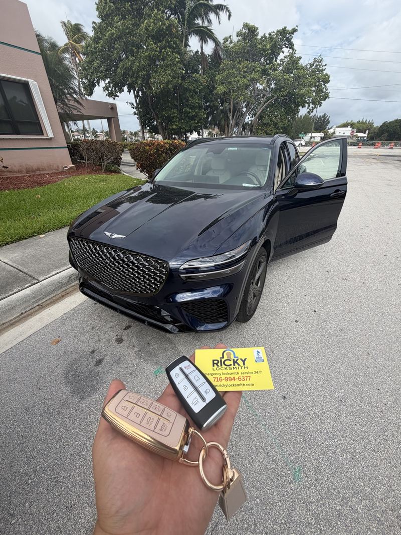 Two Genesis keys held in front of a Genesis SUV