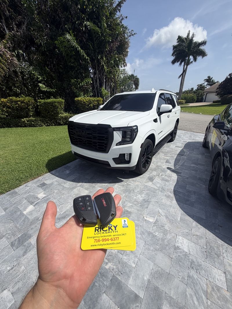 Two GMC key fobs held in front of a white GMC SUV