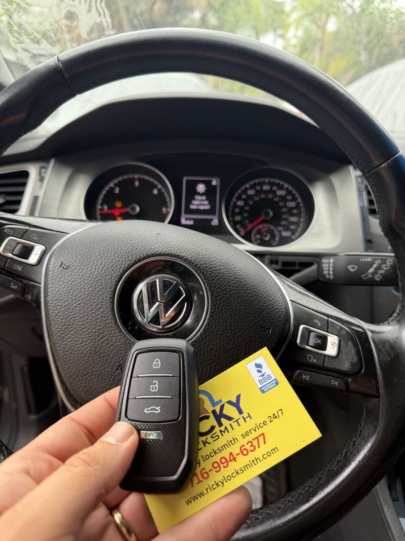 Volkswagen flip key and Ricky Locksmith card beside a steering wheel